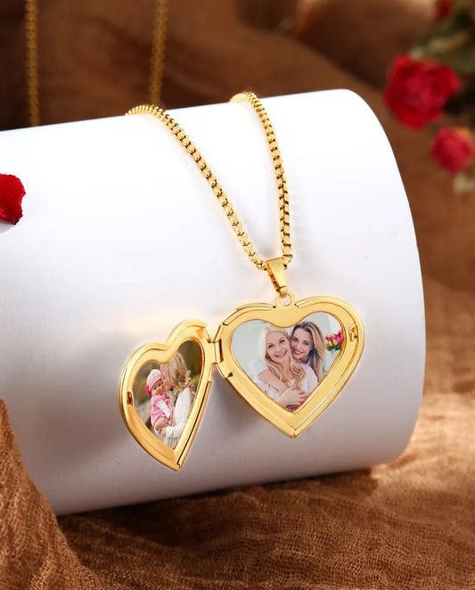 Heart locket opened to show two photos side by side inside gold frames
