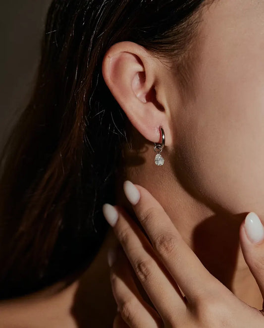 Moissanite Drop Hoop Earrings in 925 Sterling Silver - worn on a model’s ear, hand near her face
