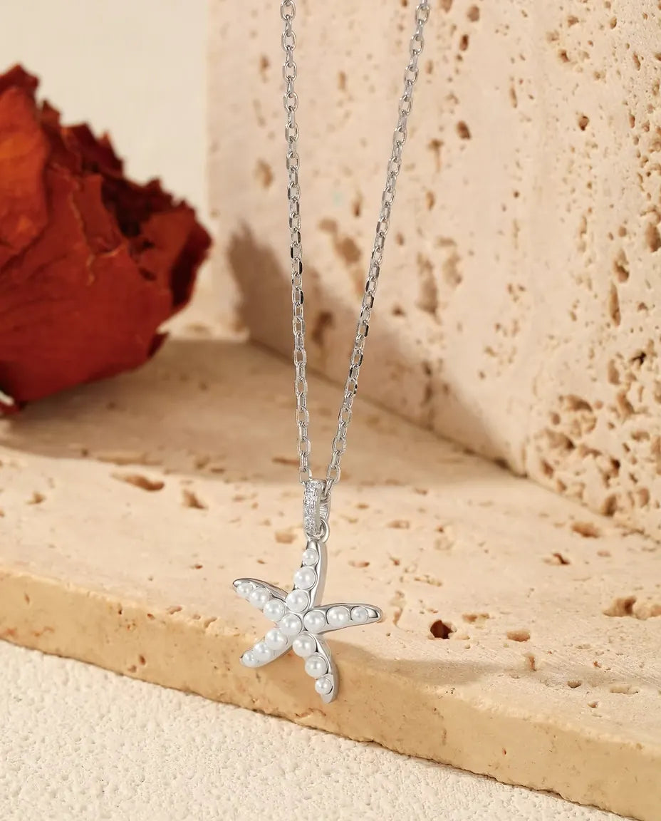Starfish Necklace in 925 Sterling Silver - pendant hanging over the edge of a travertine slab