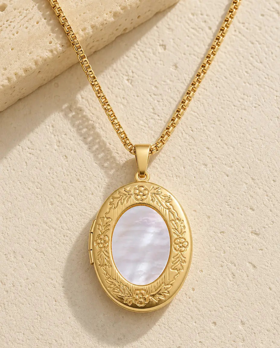 Gold oval photo locket necklace with a white mother of pearl front and embossed floral frame