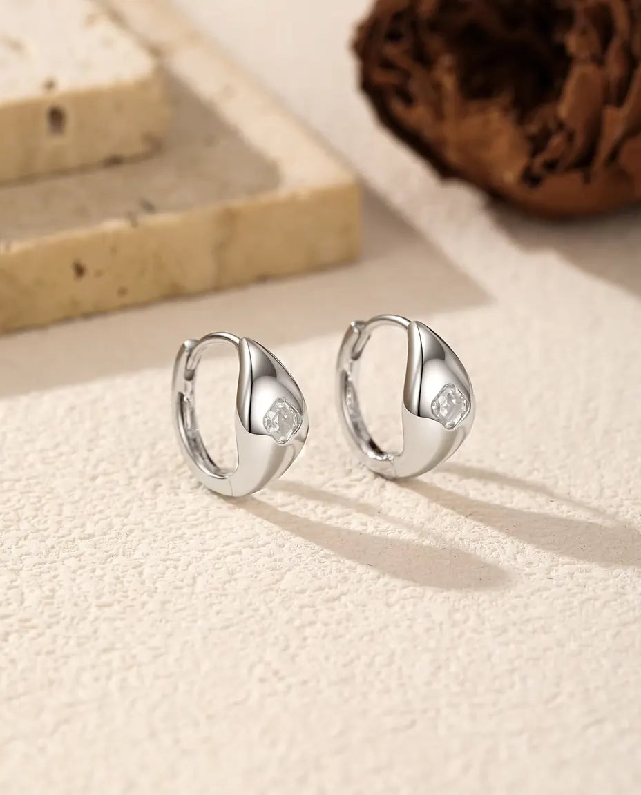 Asscher Cut Moissanite Huggie Hoop Earrings in 925 Sterling Silver - pair standing side by side on a cream textured surface