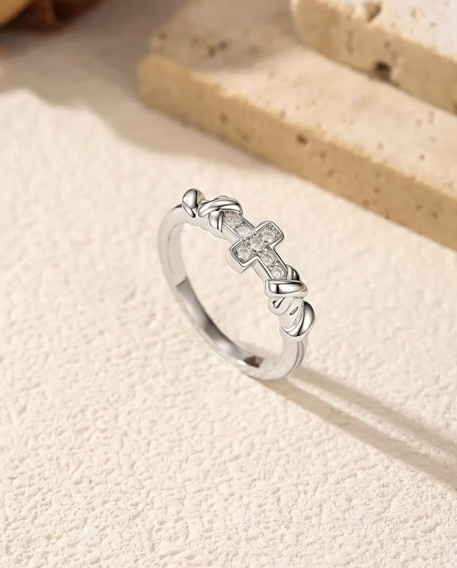 Cross Moissanite Ring in 925 Sterling Silver - standing upright beside travertine blocks, wider view