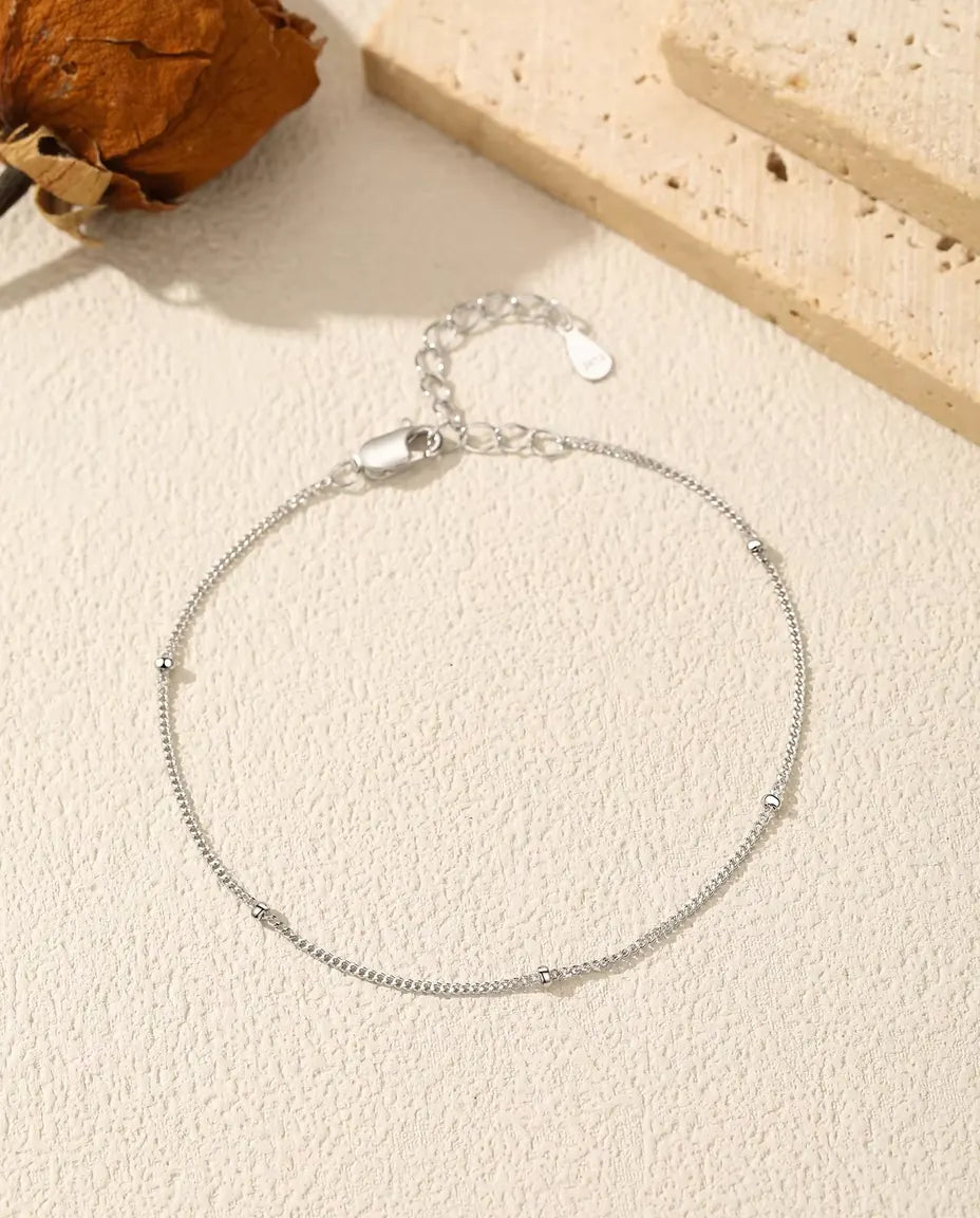 Satellite Chain Bracelet in 925 Sterling Silver - laid flat on a cream textured surface with the clasp and extender