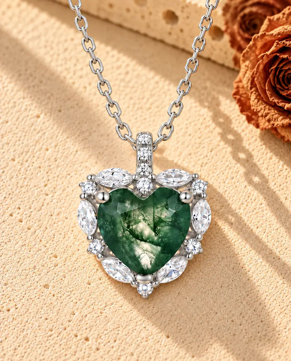 Heart Moss Agate Halo Necklace in 925 Sterling Silver - lying on a cream textured surface beside a travertine block