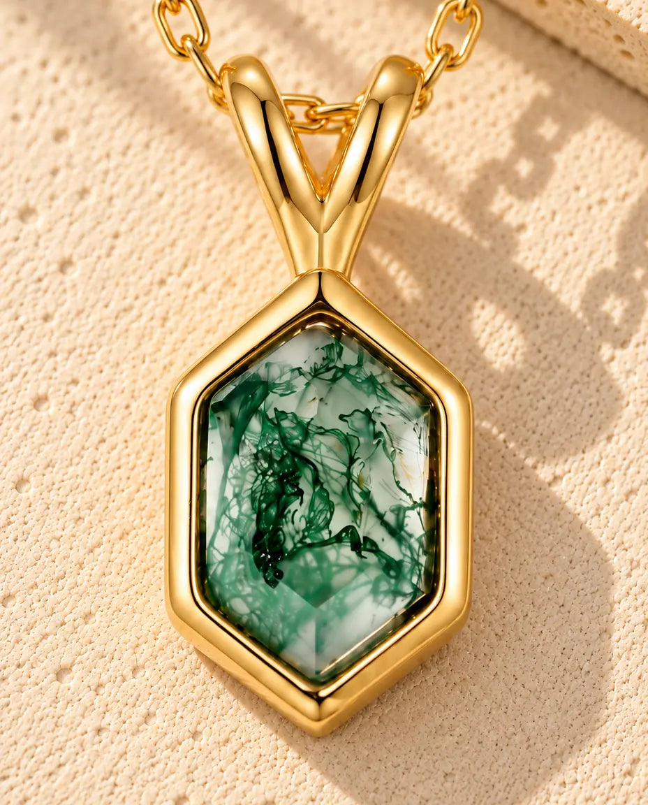 Hexagon Moss Agate Necklace in 10K Gold Plated 925 Sterling Silver - lying on a cream textured surface beside a travertine block