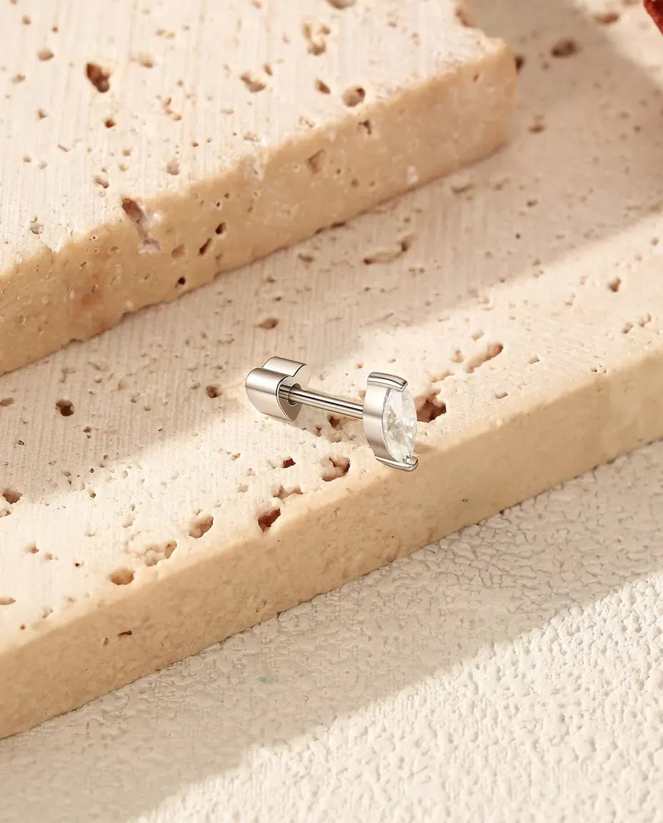 Marquise Moissanite Stud Earrings in 925 Sterling Silver - lying on the edge of a travertine slab, back attached