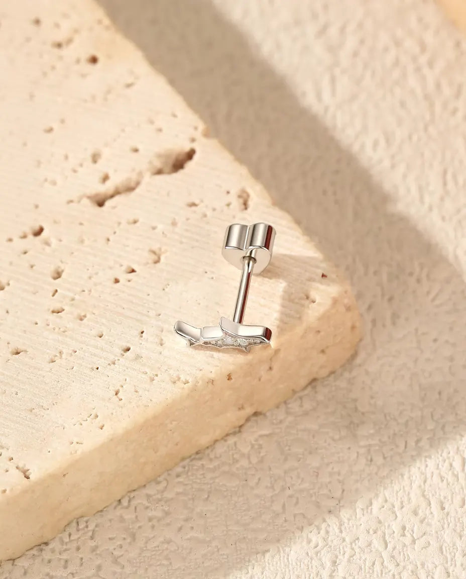 Shark Stud Earrings in 925 Sterling Silver with Moissanite - lying on the edge of a travertine slab, back attached