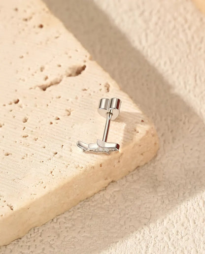 Shark Stud Earrings in 925 Sterling Silver with Moissanite - lying on the edge of a travertine slab, back attached