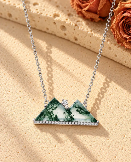 Mountain Moss Agate Necklace in 925 Sterling Silver - lying on a cream textured surface beside a travertine block