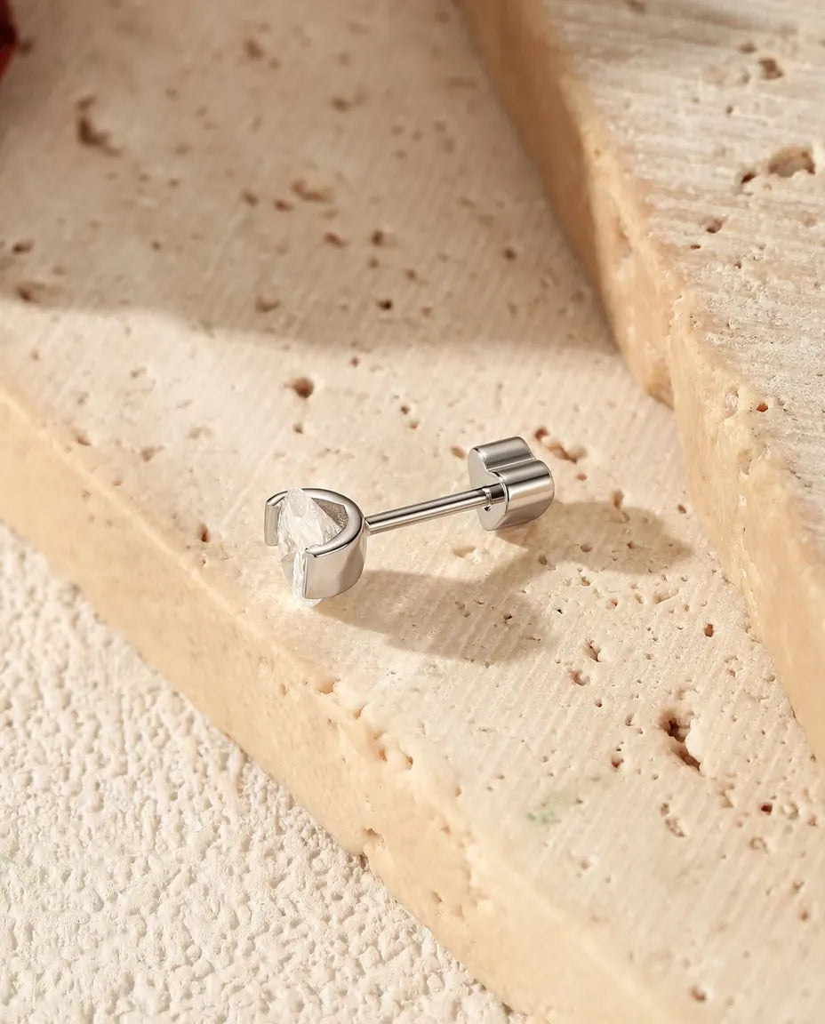 Oval Moissanite Stud Earrings in 925 Sterling Silver - lying on the edge of a travertine slab, back attached