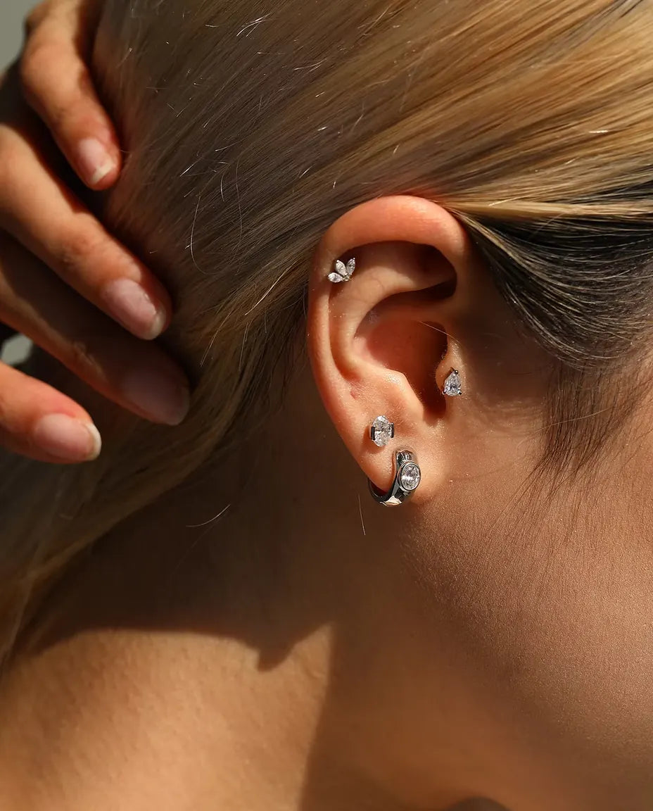 Pear Moissanite Stud Earrings in 925 Sterling Silver - worn on a model tucking her hair behind her ear
