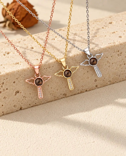 Angel wings cross projection necklaces in silver tone, gold tone and rose gold tone on travertine
