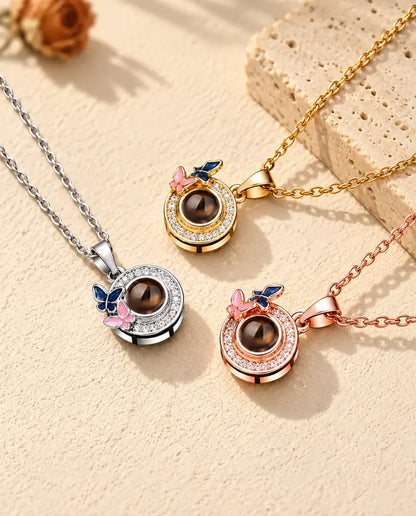 Gold tone, silver tone and rose gold tone butterfly circle necklaces beside a travertine slab