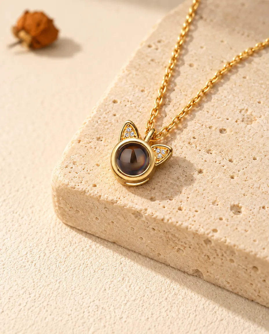 Personalised gold tone cat ear photo projection necklace on a travertine block