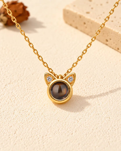 Front view of the tiny gold tone round pendant with two cat ears