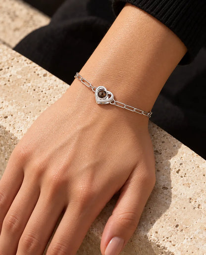 Woman wearing the silver tone double heart photo projection bracelet on her wrist in warm sunlight