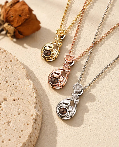Flower teardrop projection necklaces in silver tone, gold tone and rose gold tone laid diagonally