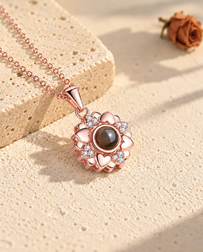 Rose gold tone heart flower projection necklace lying on plaster in warm sunlight
