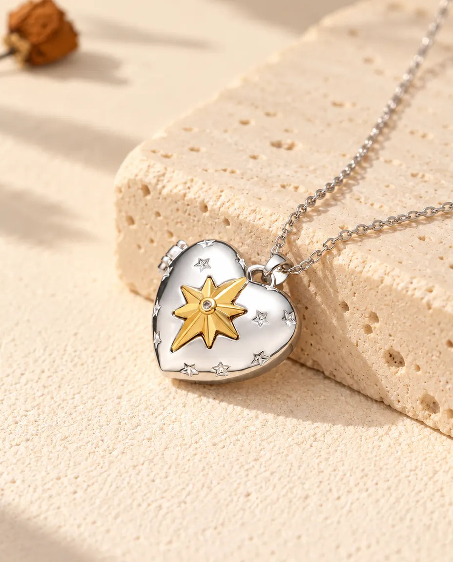 Personalised north star heart photo locket necklace in silver tone with a gold tone north star, resting on a travertine block