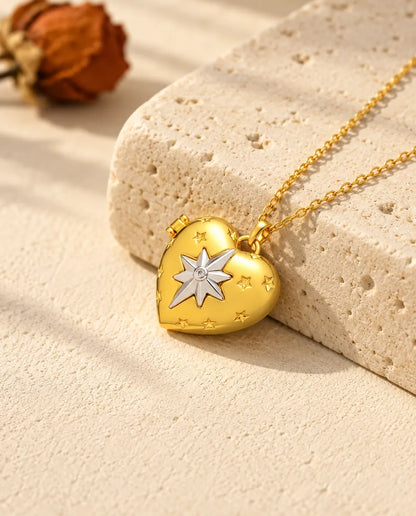 Gold tone north star heart photo locket necklace resting on a travertine block