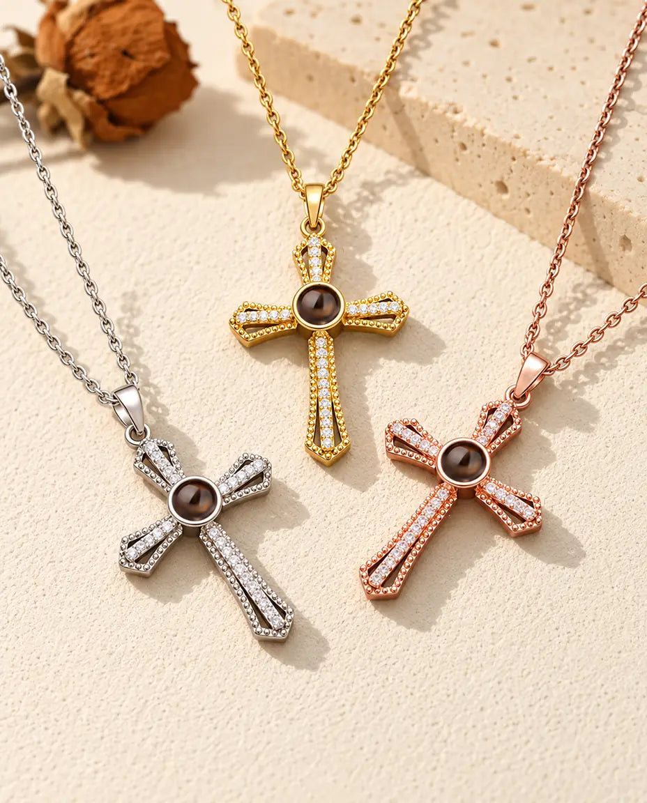 Three colours of the pave cross photo necklace laid out on cream plaster