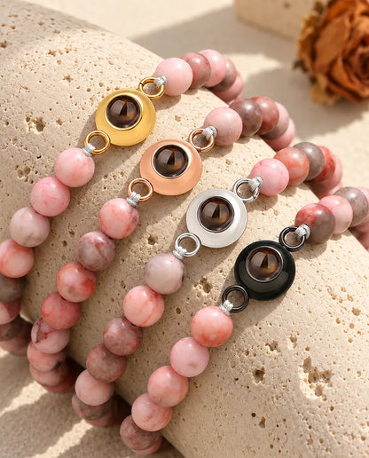 Pink speckled bead projection bracelets in each charm colour on travertine