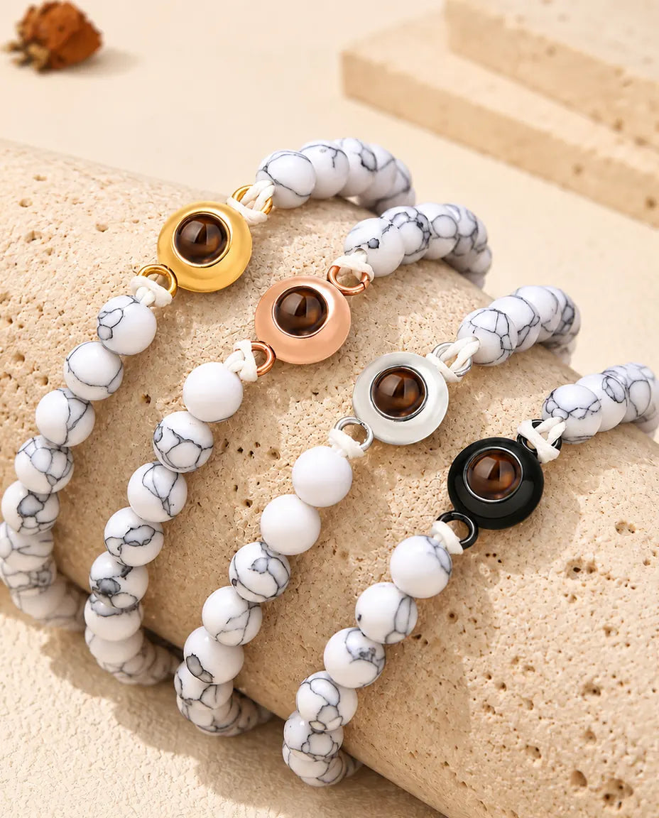 White marbled bead projection bracelets in each charm colour draped over travertine