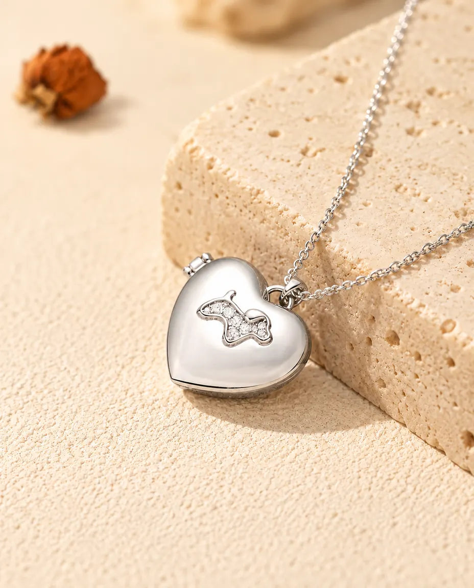Personalised puppy heart photo locket necklace in silver tone with a cubic zirconia puppy on the lid, resting on a travertine block