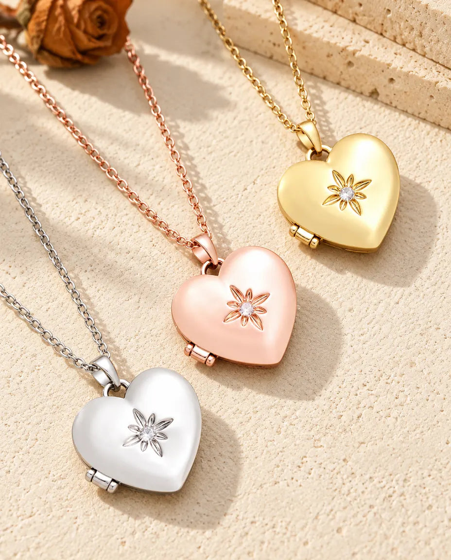 Satin flower heart photo lockets in silver tone, rose gold tone and gold tone laid diagonally on cream plaster