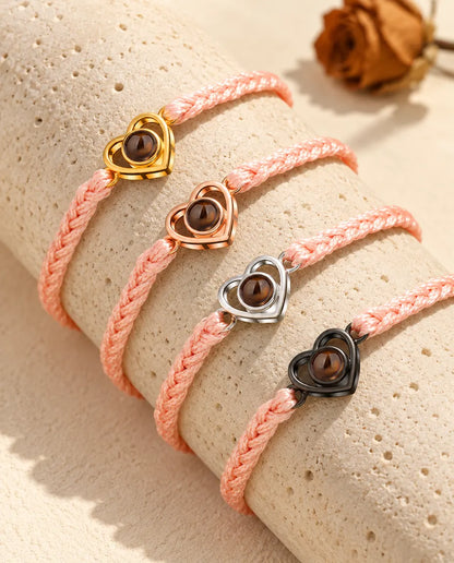 Pink braided cord open heart bracelets showing every charm colour draped over travertine