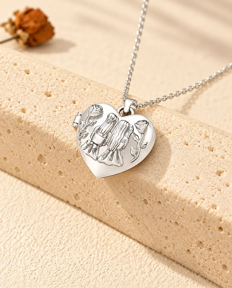 Personalised sisters heart photo locket necklace in silver tone with two girls and roses on the lid, resting on a travertine block