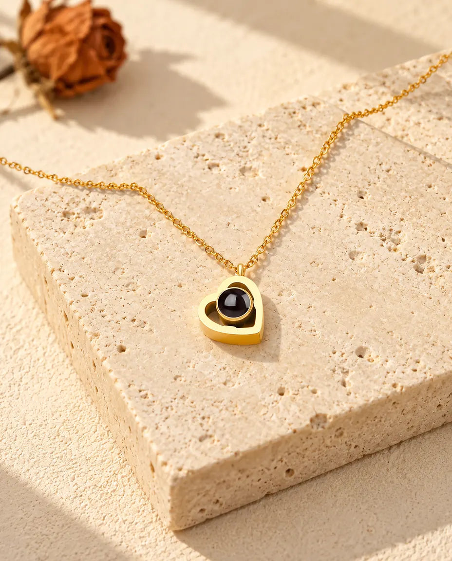 Gold tone double heart photo projection necklace lying on a travertine block