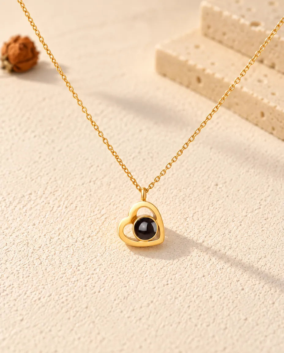 Front view of the gold tone double heart projection pendant with its dark projection stone