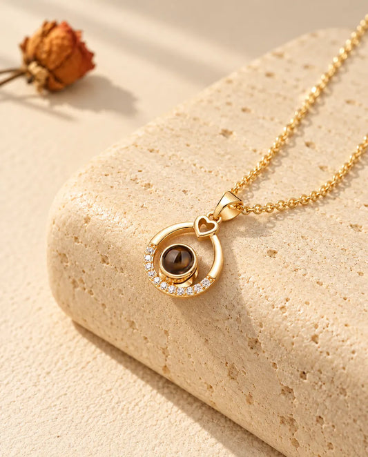 Personalised gold tone teardrop photo projection necklace with a little heart on travertine