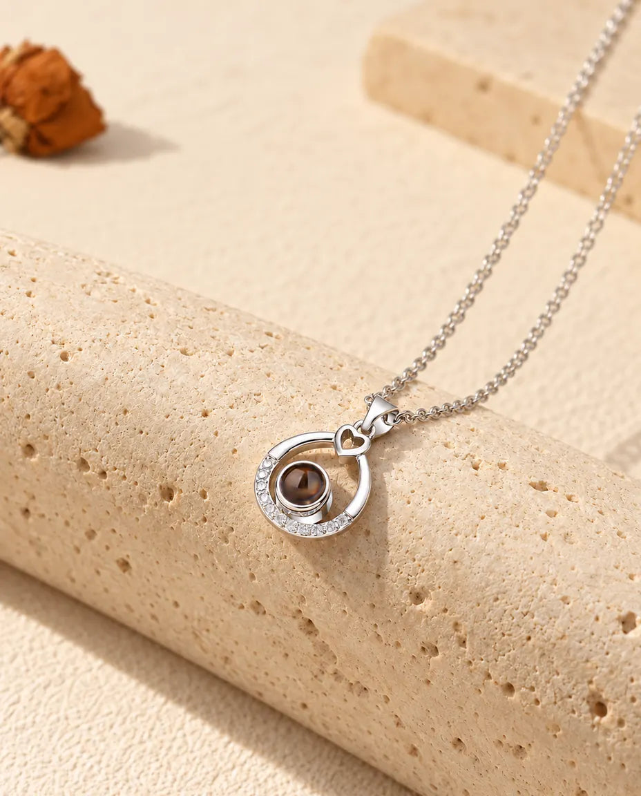 Silver tone teardrop projection necklace hanging over travertine