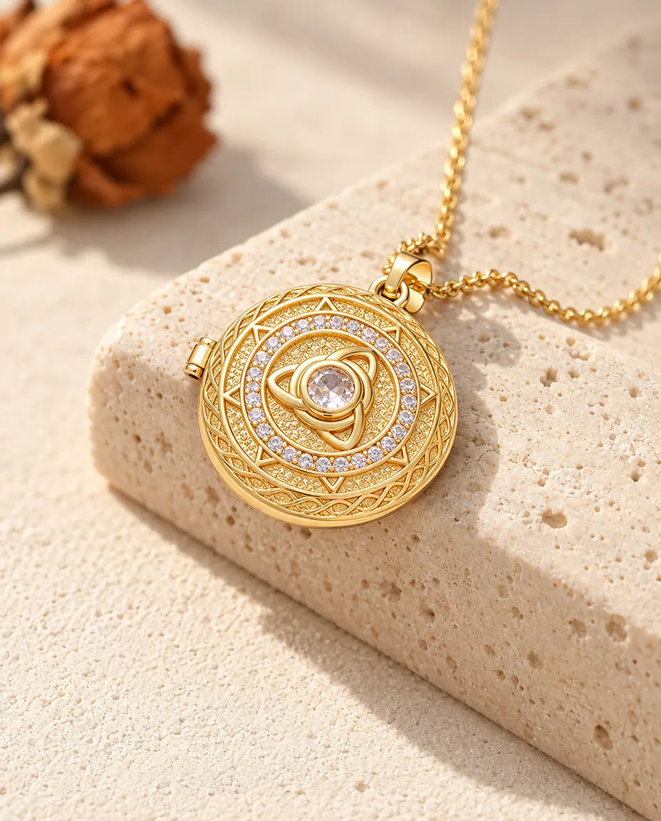 Gold tone round trinity knot locket necklace with a centre stone draped over a travertine block
