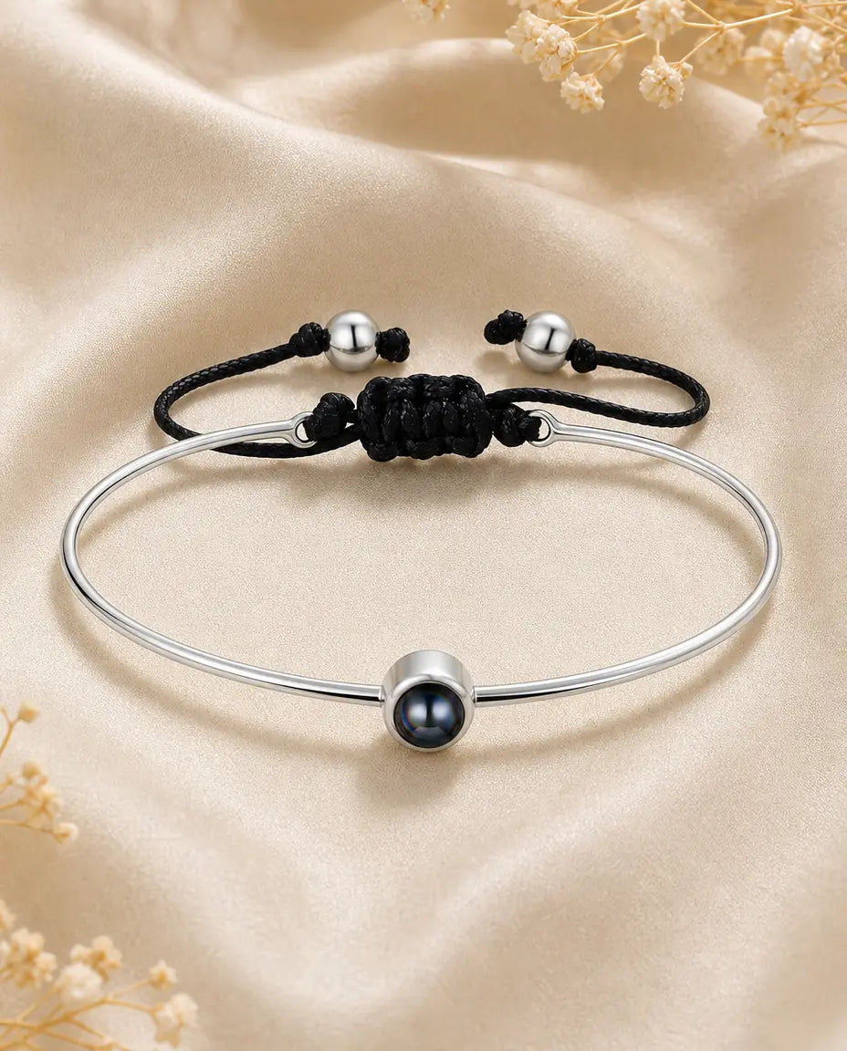 Silver photo projection bangle bracelet with black cord on ivory silk