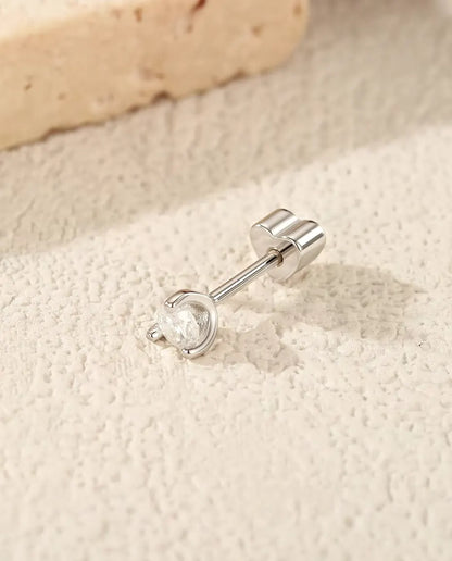 Round Moissanite Stud Earrings in 925 Sterling Silver - lying on its side on a cream textured surface, heart-shaped back on the post