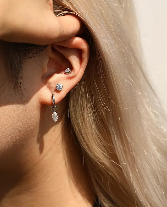 Round Moissanite Four-Prong Stud Earrings in 925 Sterling Silver - worn on a model tucking her hair behind her ear