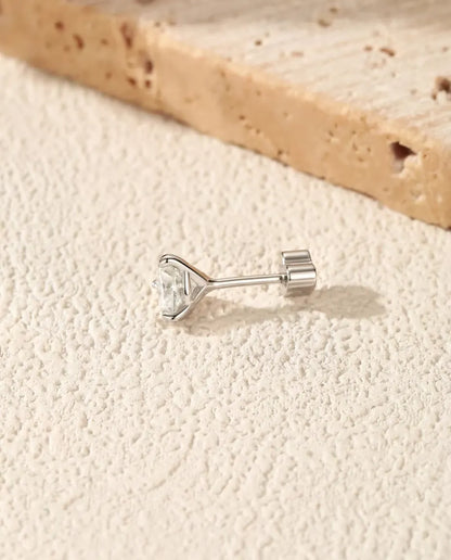 Round Moissanite Three-Prong Stud Earrings in 925 Sterling Silver - lying on its side on a cream textured surface, heart-shaped back on the post