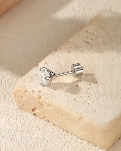 Round Moissanite Three-Prong Stud Earrings in 925 Sterling Silver - lying on the edge of a travertine slab, back attached