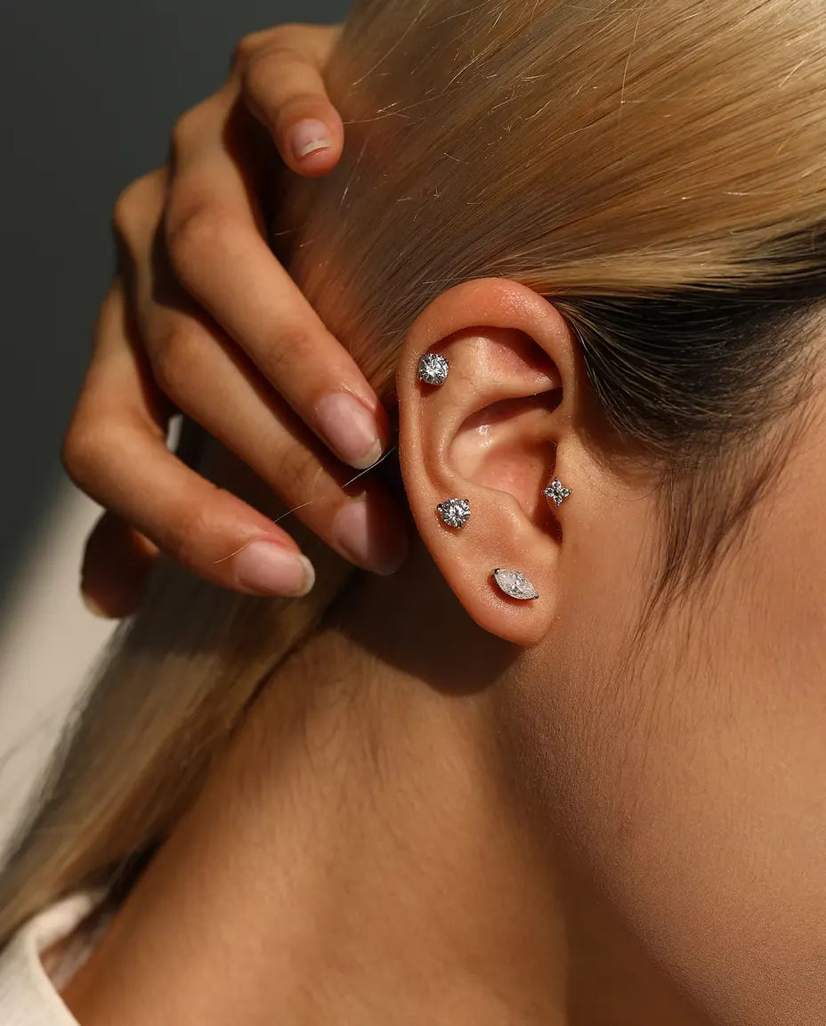 Round Moissanite Three-Prong Stud Earrings in 925 Sterling Silver - worn on a model with her hand at the back of her head
