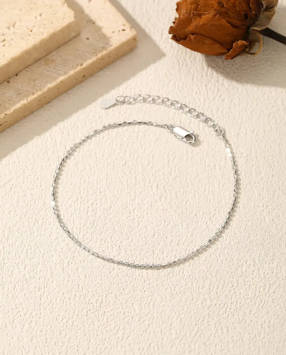 Sparkle Chain Bracelet in 925 Sterling Silver - laid flat on a cream textured surface with the clasp and extender