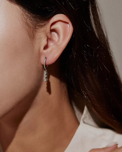 Three Stone Moissanite Drop Hoop Earrings in 925 Sterling Silver - worn on a model’s ear, close-up