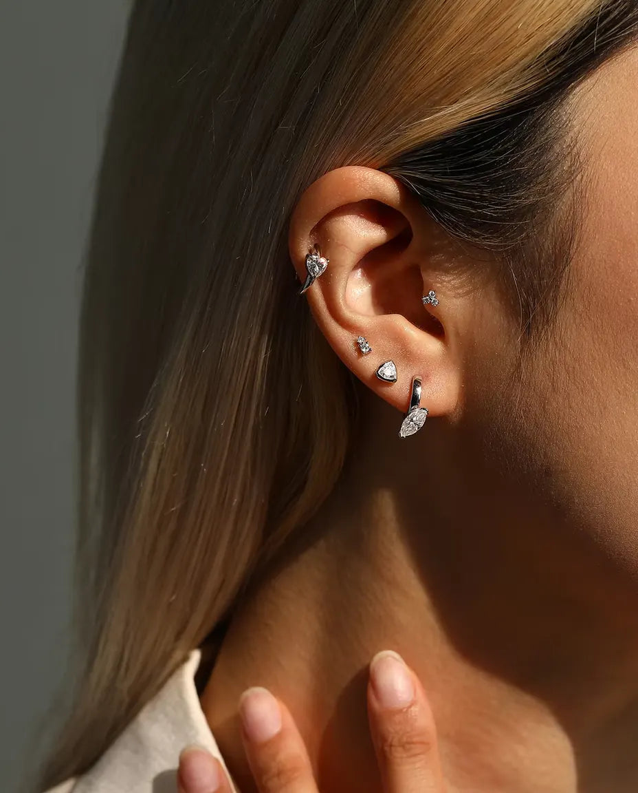 Trillion Moissanite Bezel Stud Earrings in 925 Sterling Silver - worn on a model with her hand at her neck