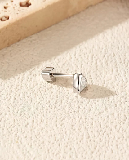 Trillion Moissanite Bezel Stud Earrings in 925 Sterling Silver - lying on its side on a cream textured surface, heart-shaped back on the post